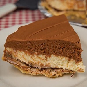 A slice of 5-layer chocolate pie showing distinct layers of crust, dark chocolate ganache, milk chocolate mousse, whipped cream, and chocolate shavings