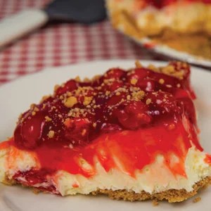 A chilled French cream pie with a graham cracker crust, topped with a thick layer of whipped cream and a glossy cherry glaze