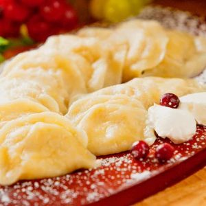 A plate of golden-brown pierogi filled with sweetened farmer's cheese, lightly drizzled with melted butter