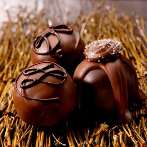 A close-up shot of hand-rolled dark chocolate truffles topped with a light dusting of cocoa powder